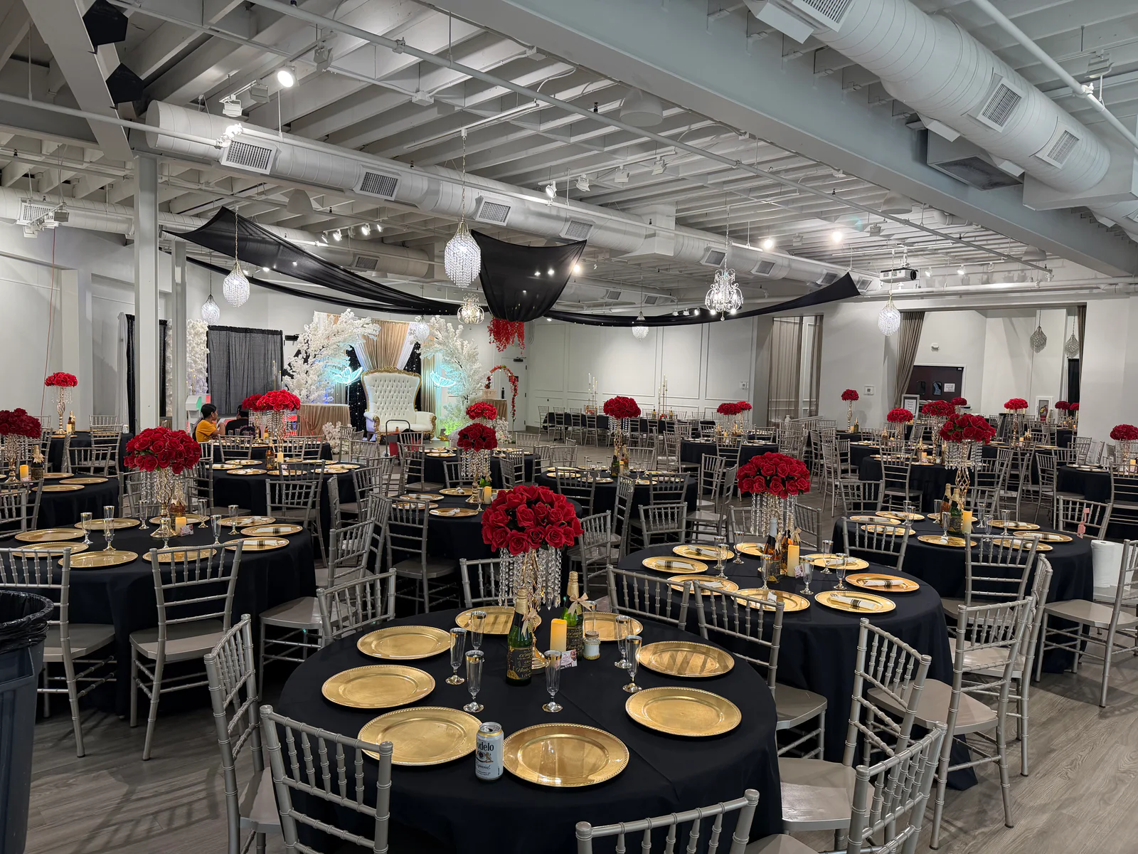 The Sterling Room arranged with round dining tables, charcoal linens, silver chairs, and gold place settings