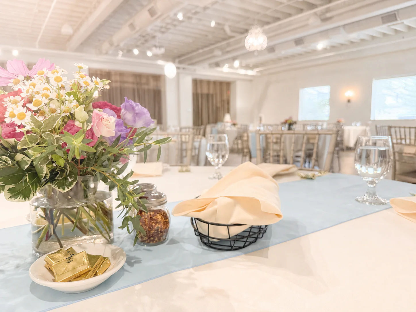 A softly lit table detail with flowers, linens, and glassware inside The Sterling Room