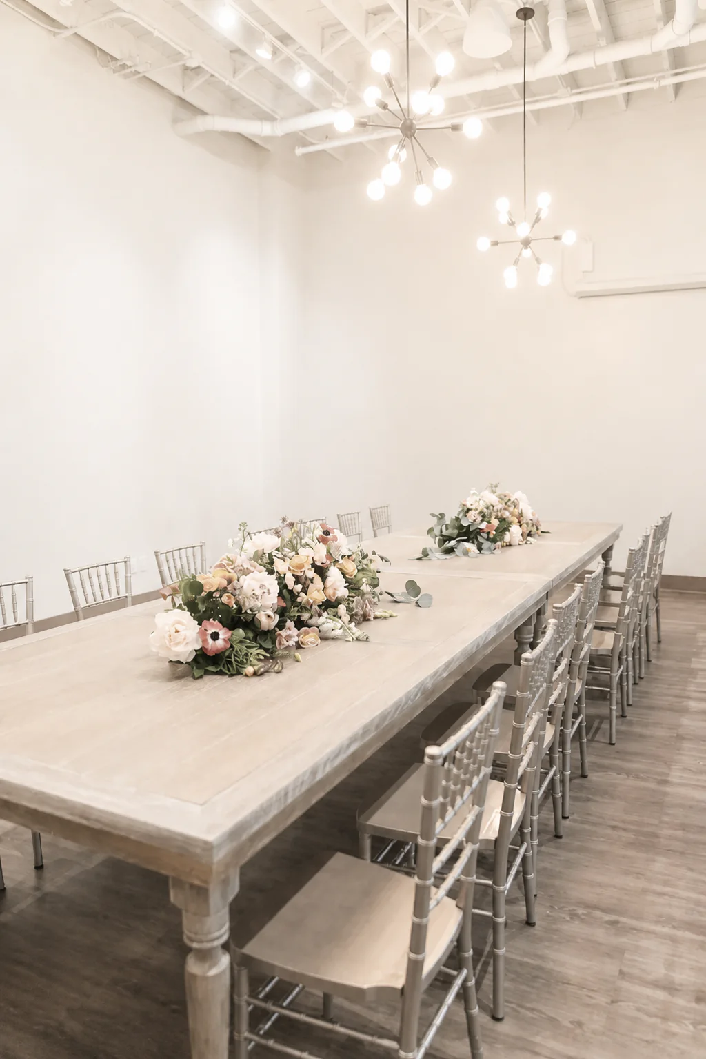 A long table with silver chairs and floral arrangements inside The Sterling Room